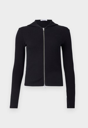 Schwarze gerippte Zip-Hoodie aus elastischem Material, mit langen Ärmeln, tailliertem Schnitt und kleiner Kapuze. Der Reißverschluss verläuft von Hals bis Saum.