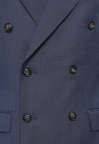 Blazer doppiopetto blu navy in tessuto testurizzato, con sei bottoni neri e due tasche laterali. Vestibilità sartoriale con rever affilati.