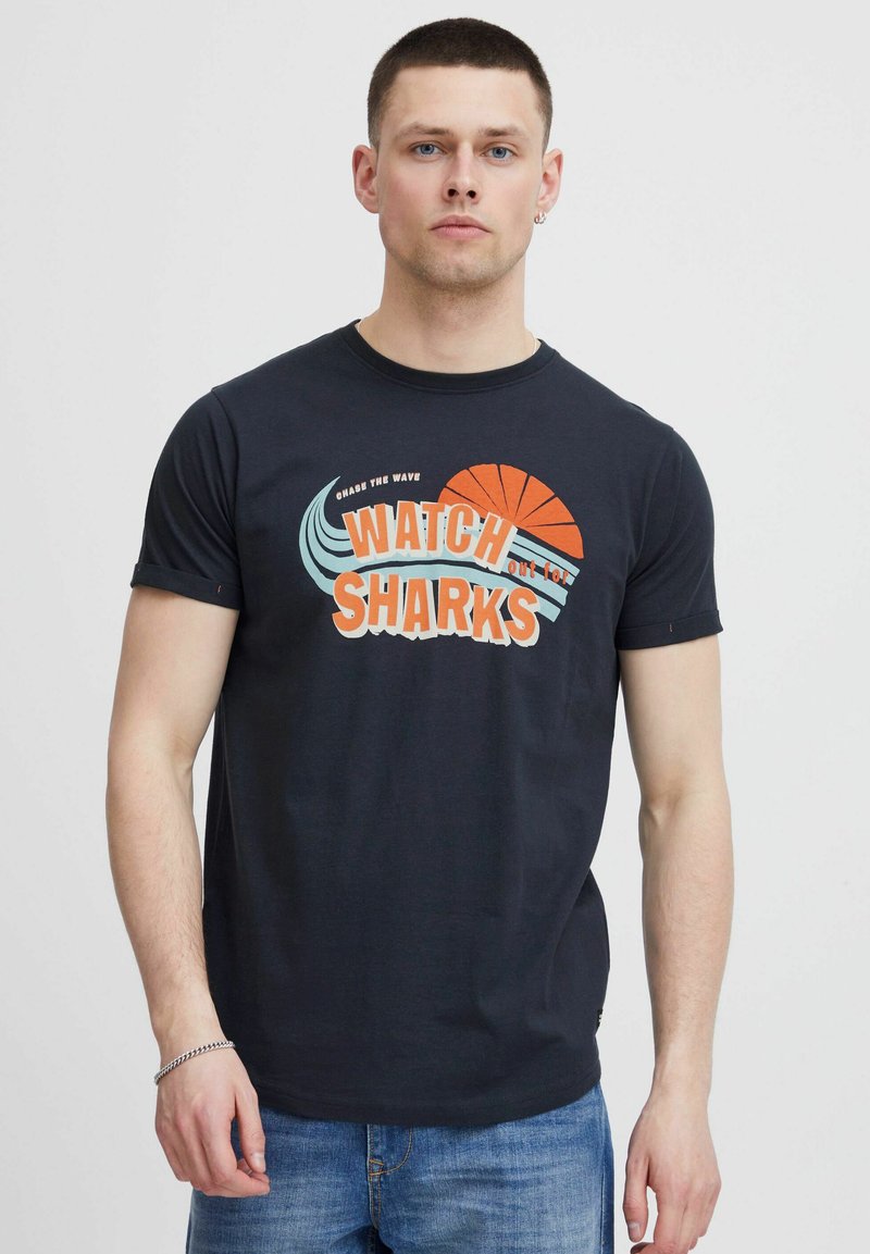 Dunkelblaues Baumwoll-T-Shirt mit einem grafischen Druck "WATCH SHARKS" in Orange und Blau, Rundhalsausschnitt und kurzen Ärmeln.