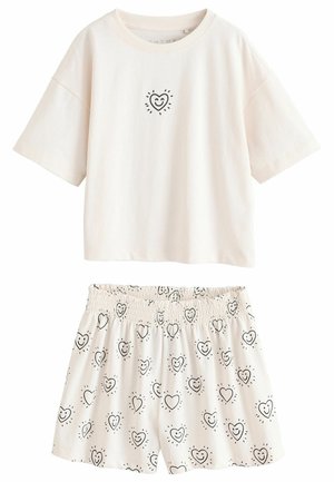 T-shirt en coton beige clair avec des manches courtes et un graphique de cœur noir. Les shorts assortis ont une taille élastique et un motif de cœurs répété.