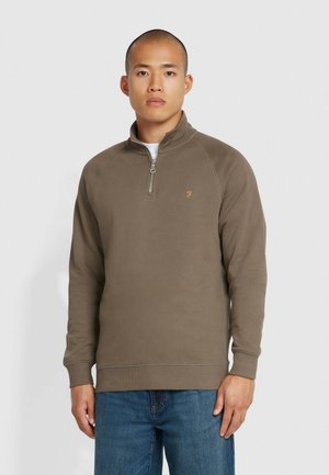 Olijfgroene zip-up sweatshirt van zacht materiaal, met een opstaande kraag, raglanmouwen en een klein oranje logo op de borst.