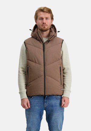 Bruine opblaasbare gilet met een ritssluiting aan de voorkant en een capuchon, voorzien van diagonale quiltstiksels, zijzakken en een zwarte rits. Draagt over een licht truitje.