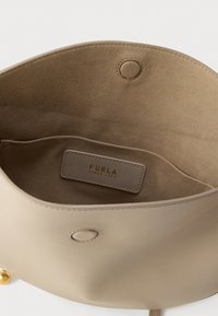 Εσωτερικό μπεζ δερμάτινης τσάντας με λεία, απαλή υφή και μία τσέπη που φέρει μια ετικέτα με την επιγραφή "Furla Since 1927".