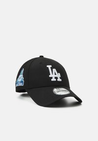 Schwarze Baseballmütze mit weißem "LA"-Logo, aufgesticktem blauen Patch an der Seite, gebogenem Schirm und verstellbarem Riemen auf der Rückseite.