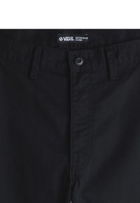 Sorte chinos med flad front, knaplukning og bæltestropper. Har VANS-brandingtag nær taljen. Glat bomuldsstof.