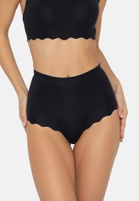 Hooggewaardeerde zwarte bikini-broek met een scalloped randontwerp. Gemaakt van glad materiaal, het heeft een naadloze constructie voor comfort.