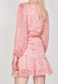 Rosa blommig klänning i lätt material, med långa ärmar, en utsvängd kjol och ett nyckelhål bak.