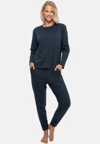 Marinblått loungedräktset med långärmad topp och joggerbyxor. Mjuk tyg, avslappnad passform, ribbade muddar och sidofickor.