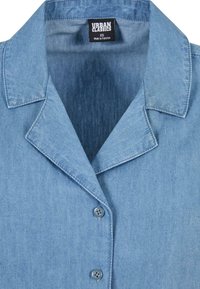 Lyseblå denimskjorte med notched krage, med knappelukking foran og to blå knapper. Laget av myk, teksturert stoff.