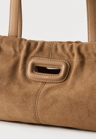 Καφέ τσάντα από σουέντ με ραμμένες λεπτομέρειες, ορθογώνια δερμάτινη λαβή με κοπή και κοντό λουρί λαβής.