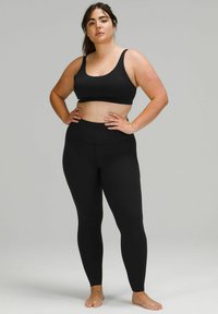 Juodas sportinis liemenukas ir leggingų komplektas, pagamintas iš tamprios medžiagos. Pasižymi prigludusia dizaino forma su plačiomis petnešėlėmis ir aukšto liemens leggingais.
