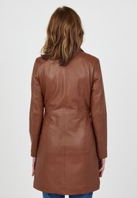 Bruine leren jas met een getailleerde snit, lange mouwen en een middellange ontwerp. Glad textuur met minimale zichtbare naden.