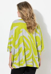 Grau und limonengrün gemusterte Bluse mit lockerer Passform, gesenkten Schultern und mittellangen Ärmeln. Sanfte Textur mit fließendem Design.