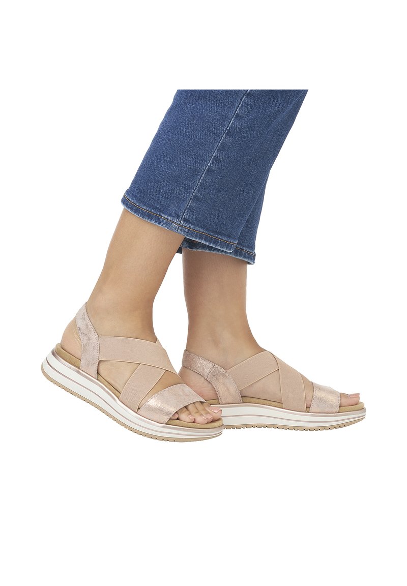 Light pink sandals featuring a cross-strap design, soft textured material, and a cushioned white sole with a tan accent.