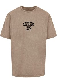 Brun oversized t-skjorte laget av bomull med rund hals. Har svart "RANDOM LIFE" tekst i en bølgete font på forsiden.