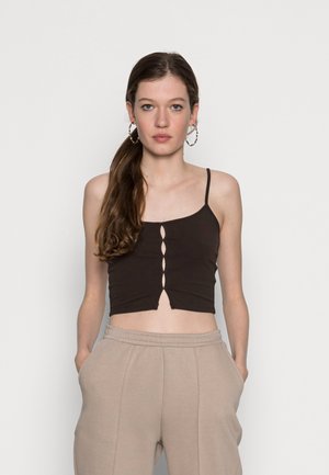Top cropped castanho com alças finas, apresentando um detalhe de recorte na frente, combinado com calças de moletom cinza claro.