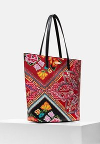 Sac fourre-tout rouge avec des motifs floraux colorés, un design diagonal et des poignées texturées noires. Fabriqué en tissu durable avec un intérieur spacieux.