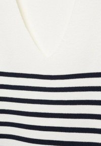 Tissu blanc à fines rayures horizontales noires et détail d'encolure en forme de V.