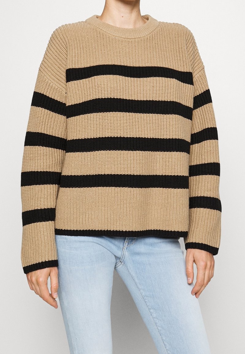 Beige gebreide sweater met zwarte horizontale strepen, ronde halslijn en lange mouwen, met een geribbelde textuur en een ontspannen pasvorm.