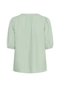 Blouse vert clair avec une finition texturée et froissée. Présente des manches bouffantes et un col rond. Design simple et ample.