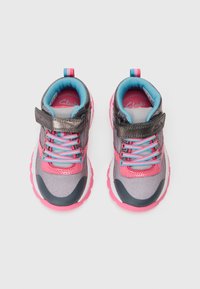 Par de zapatillas deportivas para niños en rosa, gris y azul con correas de gancho y bucle y cordones multicolores, vistas desde arriba sobre un fondo blanco.