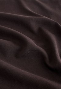 Tissu brun foncé texturé avec une élasticité subtile et des côtes horizontales, mettant en valeur un drapé doux et des détails de surface lisses.