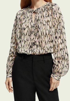 Chemisier à manches longues en tissu doux à motifs, avec un décolleté en keyhole. Les couleurs incluent rose, noir et crème. Poignets froncés et subtil éclat.