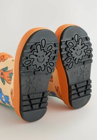 Gummistiefel für Kinder mit einem bunten Blumenmuster, orangefarbenen Sohlen, schwarzem Gummiprofil und einem verspielten Spritzdesign an der Unterseite.