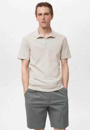 Beige Poloshirt mit kurzen Ärmeln und flachem Kragen, kombiniert mit grauen Shorts mit Nadelstreifen. Der Stoff erscheint glatt und leicht.