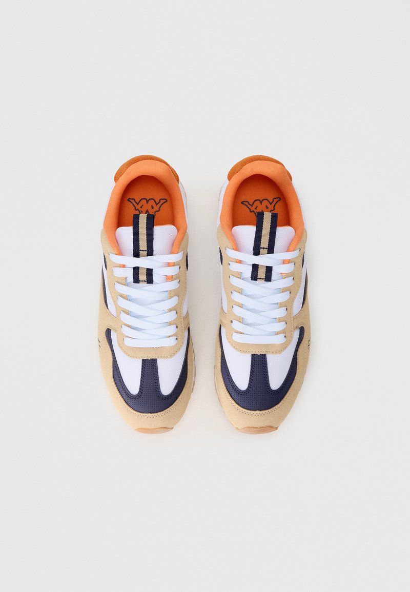 Beige und marineblaue Sneakers mit einem Obermaterial aus Stoff und Wildleder, weißen Schnürsenkeln, orangefarbenem Futter und einer strukturierten Sohle mit einer leicht tanfarbenen Umrandung.