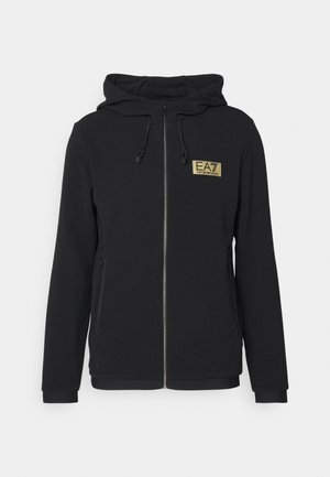 Sudadera negra con cremallera, hecha de un tejido texturizado, con capucha ajustable, bolsillos laterales y un parche de logo dorado en el pecho.