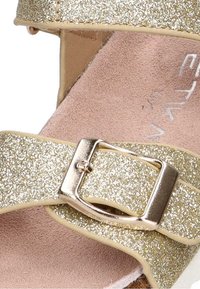Sandalias de purpurina dorada con una tira ancha, hebilla en tono dorado y forro interior de color rosa suave. Presentan una suela plana y una superficie texturizada.