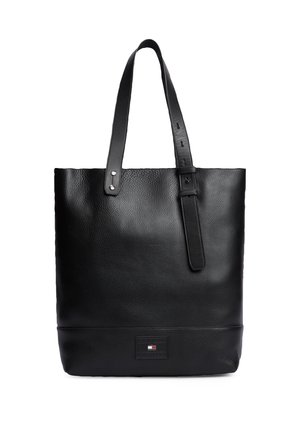 Bolso tote de cuero negro con dos asas, una ajustable con hebilla, y un pequeño parche rectangular con logo cerca del centro inferior.