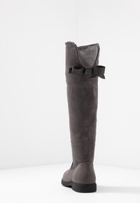 Šedá semišová kozačka ke kolenu s kulatou špičkou, měkkou podšívkou a černou stuhou na horní části. Plochá gumová podrážka pro pohodlí.