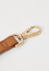 Cinturino in pelle marrone con texture e fermaglio in metallo dorato. Il fermaglio presenta un logo inciso "VALENTINO" per l'identificazione.