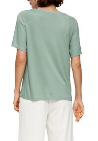 Mintgrünes Kurzarmshirt mit lässigem Schnitt, glatter Textur und rundem Halsausschnitt. Seitenschlitze sorgen für Details am Saum.