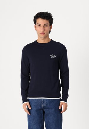 Navy Crewneck-Sweatshirt aus Baumwolle, mit weißen Rippbündchen und -saum, kleinem Logo auf der Brust und glatter Oberfläche.