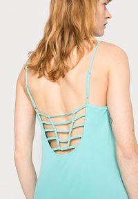 Um vestido azul claro com costas baixas, design de tiras cruzadas, alças finas ajustáveis e textura de tecido suave.