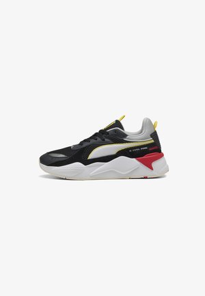 Black and gray athletic sneaker with mesh and suede upper, yellow and red accents, thick white midsole, and rounded rubber outsole.