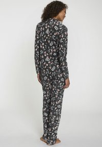 Floral-gebloemd pyjama set in donkergrijs. Het langlevende shirt en de bijpassende broek hebben roze en witte bloemen op een zachte stof.