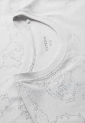 Lähikuva valkoisen puuvillaisen t-paidan kauluksesta, jossa on hentoa harmaata karttajäljitelmää ja näkyvissä oleva tuotemerkki, jossa lukee "ombre M16".