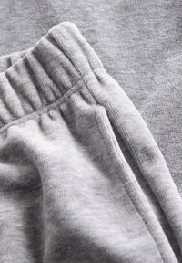 Gray fleece fabric with a soft texture, featuring an elastic waistband and side seam details. Visible folds and stitching accents.