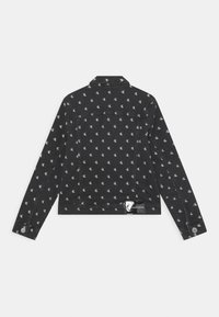 Giacca di jeans nera con un motivo logo bianco su tutta la superficie, con colletto strutturato, maniche lunghe e dettagli con bottoni a pressione sui polsini.