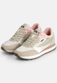 Baskets beiges et blanches avec des accents roses, en daim et matériaux synthétiques, dotées d'une semelle rembourrée et d'un logo de marque sur le côté.