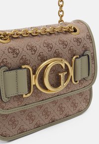 Brązowa torebka z tkaniny z wytłoczonym wzorem logo, złotymi akcesoriami i zielonym skórzanym akcentem. Posiada łańcuszkowy pasek i zapięcie na klamrę.