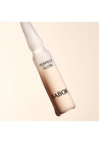 Sérum Perfect Glow de Babor dans une ampoule en verre clair, avec un capuchon blanc et une finition lisse en dégradé du blanc au beige pâle.
