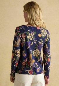 Granatowa bluzka z długim rękawem z żywym wzorem florystycznym i ptakami w odcieniach złota, różu i zieleni. Gładki materiał z okrągłym dekoltem.