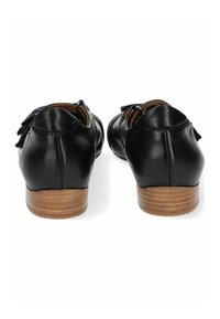 Zapatos de cuero negro con un tacón de madera bajo, con punta redondeada y detalles decorativos en la parte trasera. Textura suave y diseño clásico.