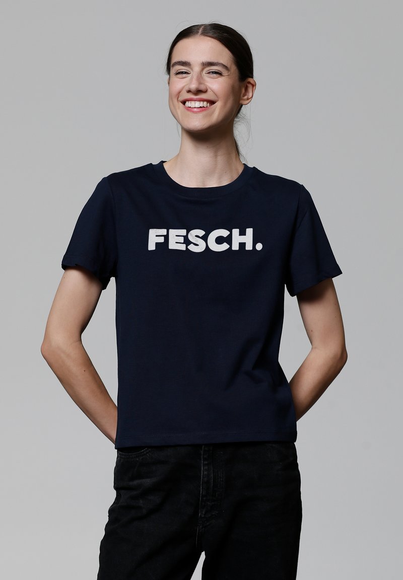 Marineblaue Baumwoll-T-Shirt mit rundem Halsausschnitt, auf dem die Aufschrift "FESCH." in fetten weißen Buchstaben über der Brust steht. Kurzärmelig.