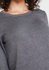 Maglione grigio lavorato a maglia con scollatura rotonda, texture liscia e forma aderente, caratterizzato da un leggero coste lungo il colletto e le cuciture.